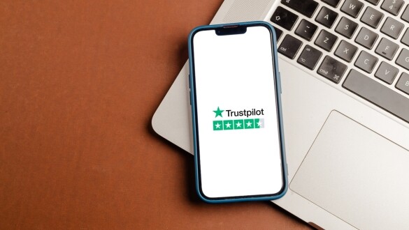 Ein Handy liegt auf einem Macbook, Trustpilot ist auf dem Display zum Bewerten